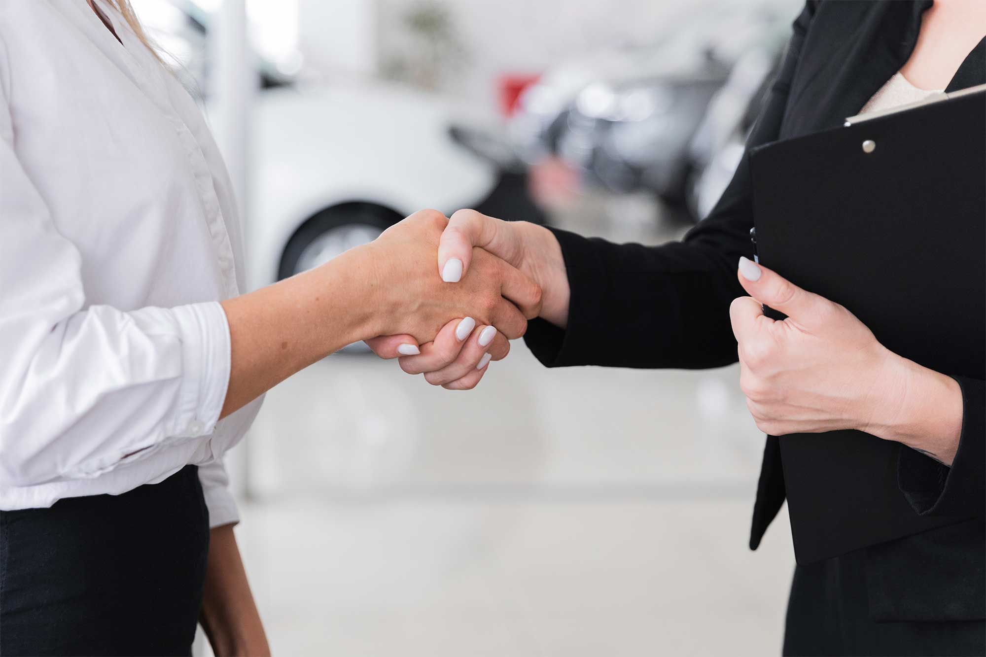 women-shaking-hands-car-show-room